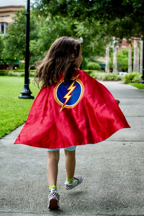 little girl wearing a superhero cape