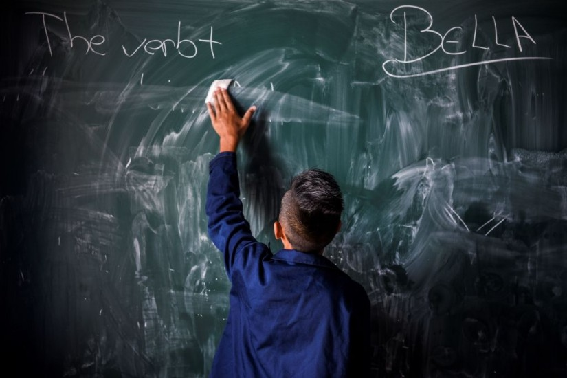 A kid erasing words on a black board